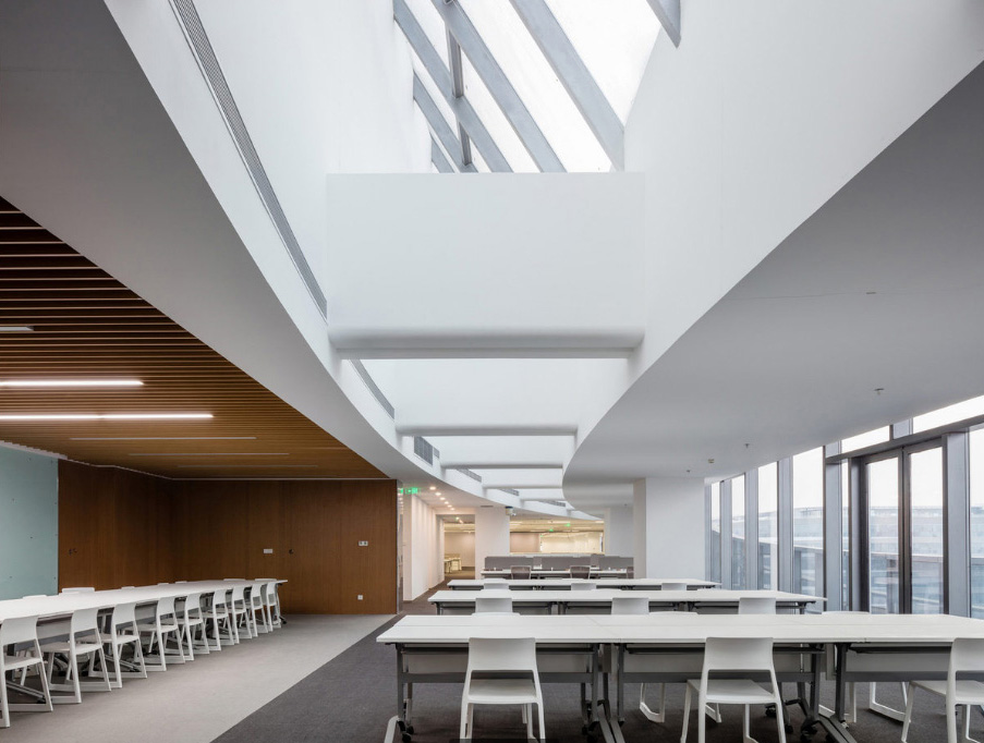 Escritório Sina Plaza, China, com evidente conceito minimalista: móveis neutros, amplos espaços de circulação, pé direito alto, iluminação clara e adequada.